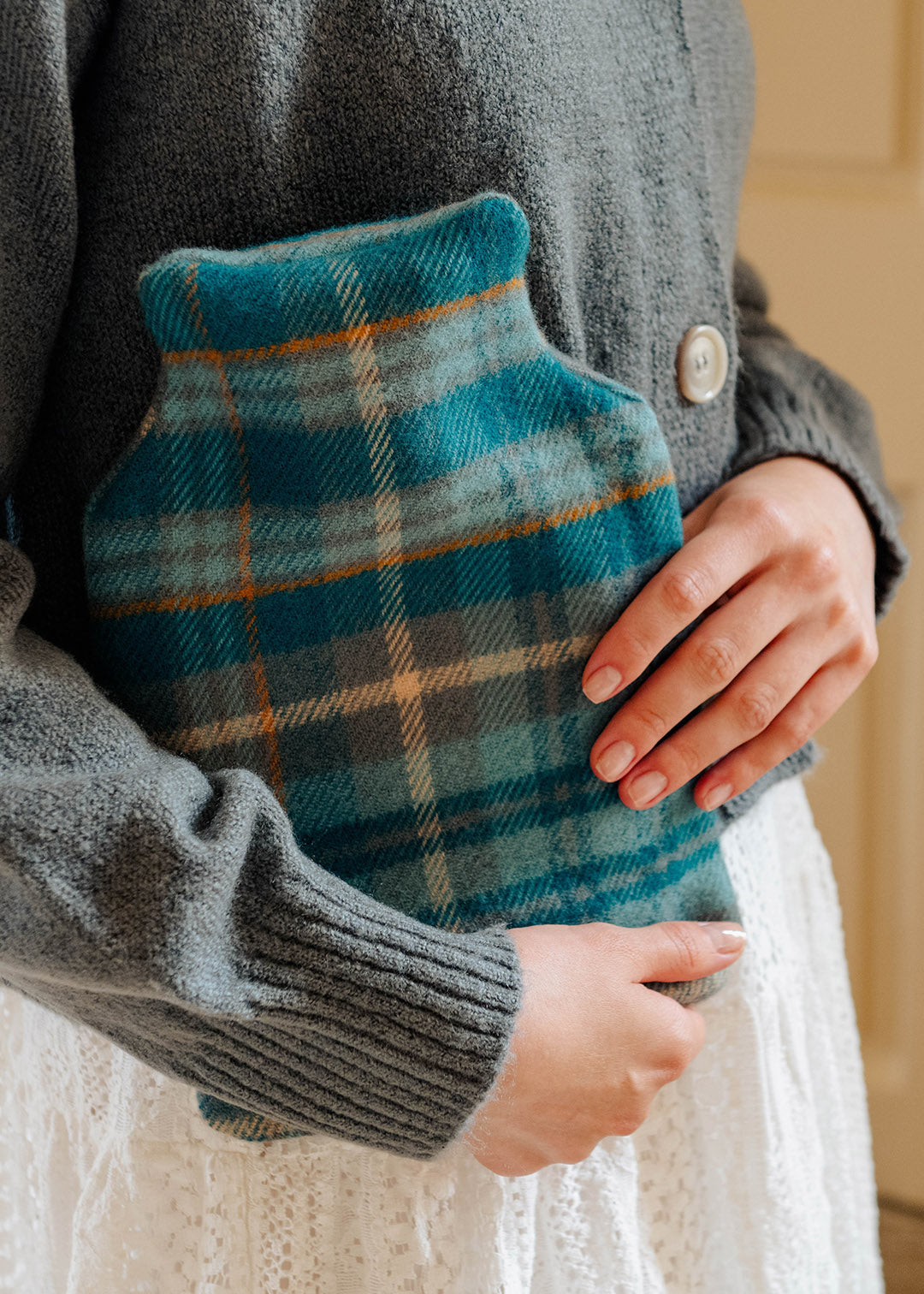 Model holding a lambswool teal tartan hot water bottle.