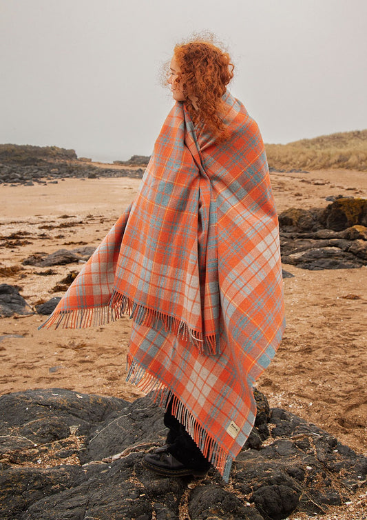 Bright coral orange check blanket with stripes of light blue and teal.  Photographed on Gullane Beach.