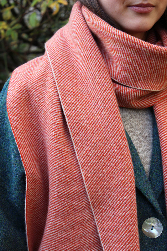Designed with a subtle oversized chevron pattern in deep orange and cream, this scarf is a modern take on a classic shawl.