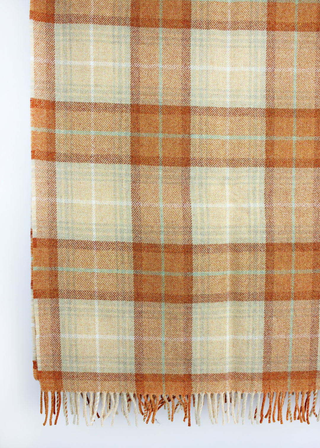 Plaid wool blanket with orange and beige colours on a white background.