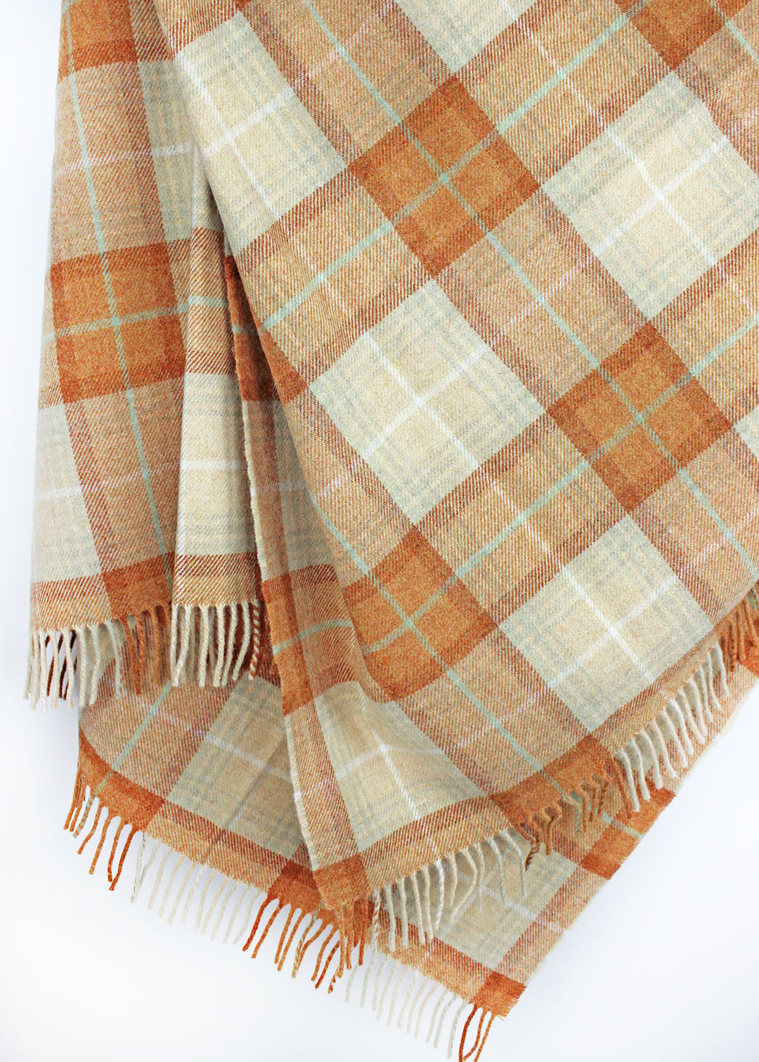 Plaid wool blanket with orange and beige colours on a white background.
