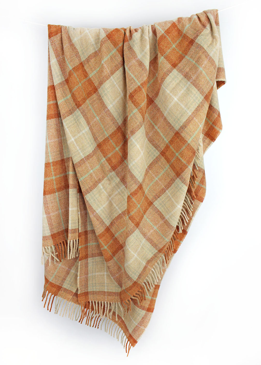 Plaid wool blanket with orange and beige colours on a white background.