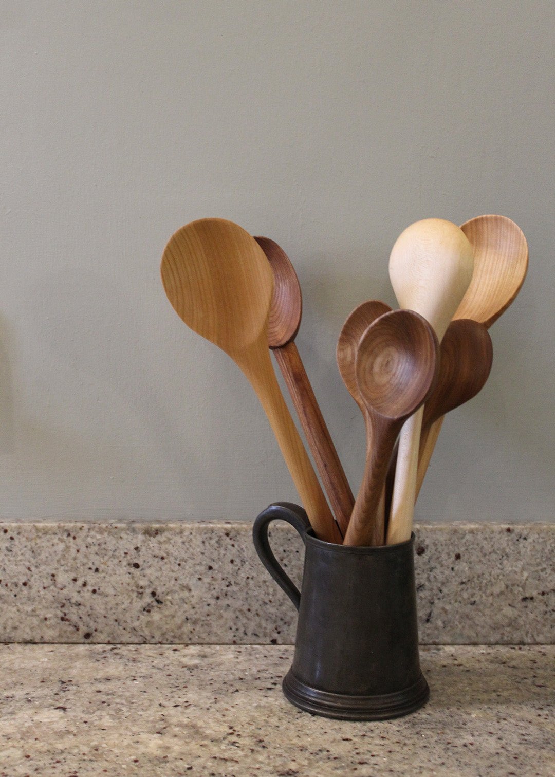 Big stirrers and porridge hard carved wooden spoons in a jug. Scottish Textiles Showcase.