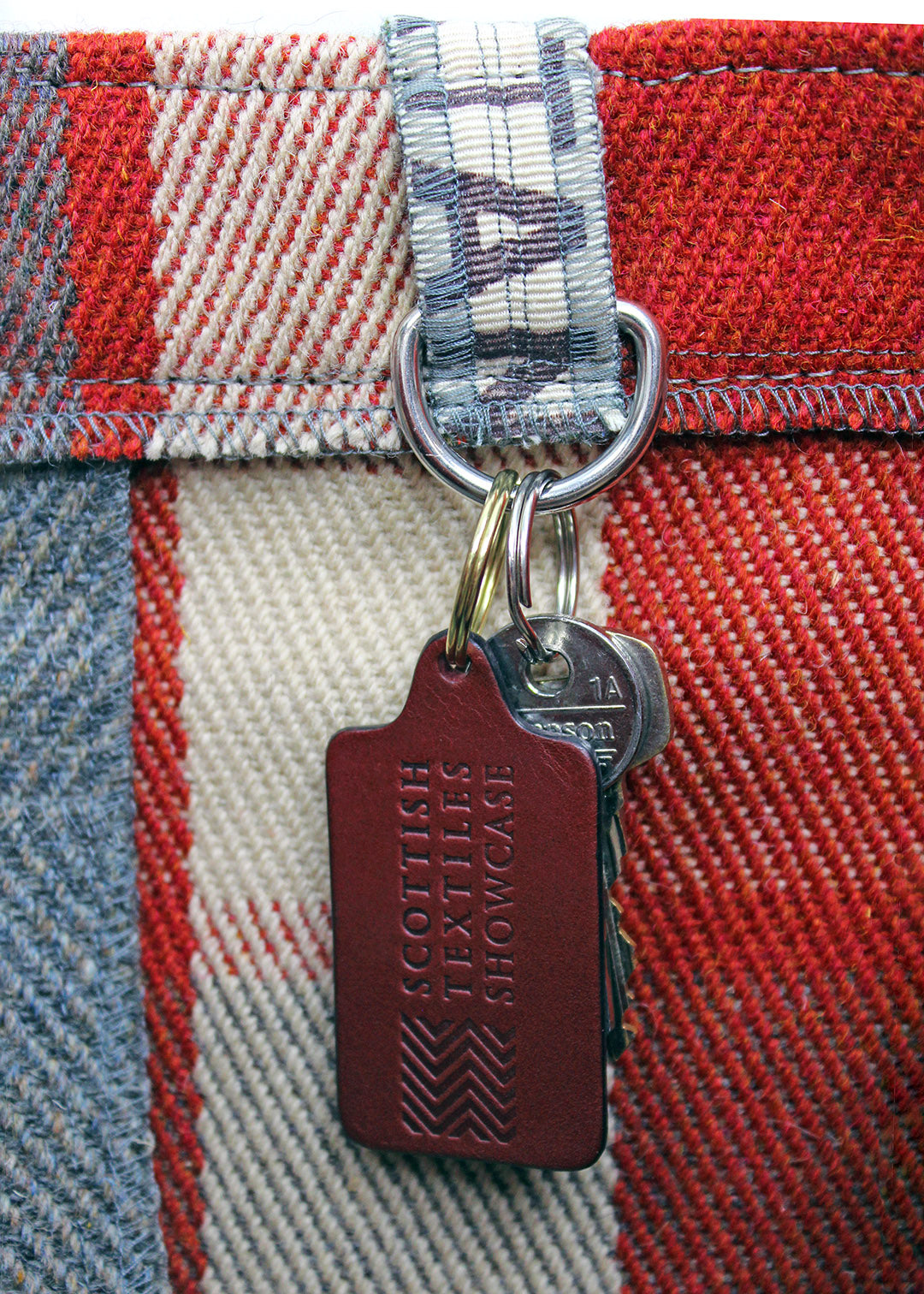 Handcrafted leather key ring in a burgundy, embossed with our Scottish Textiles Showcase logo.