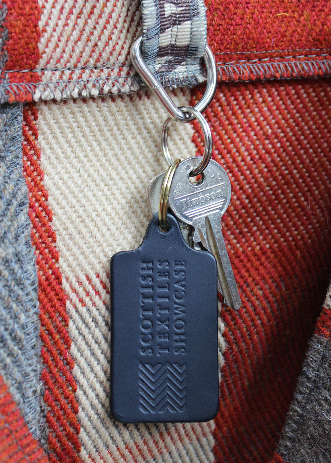Handcrafted leather key ring in navy, embossed with our Scottish Textiles Showcase logo.