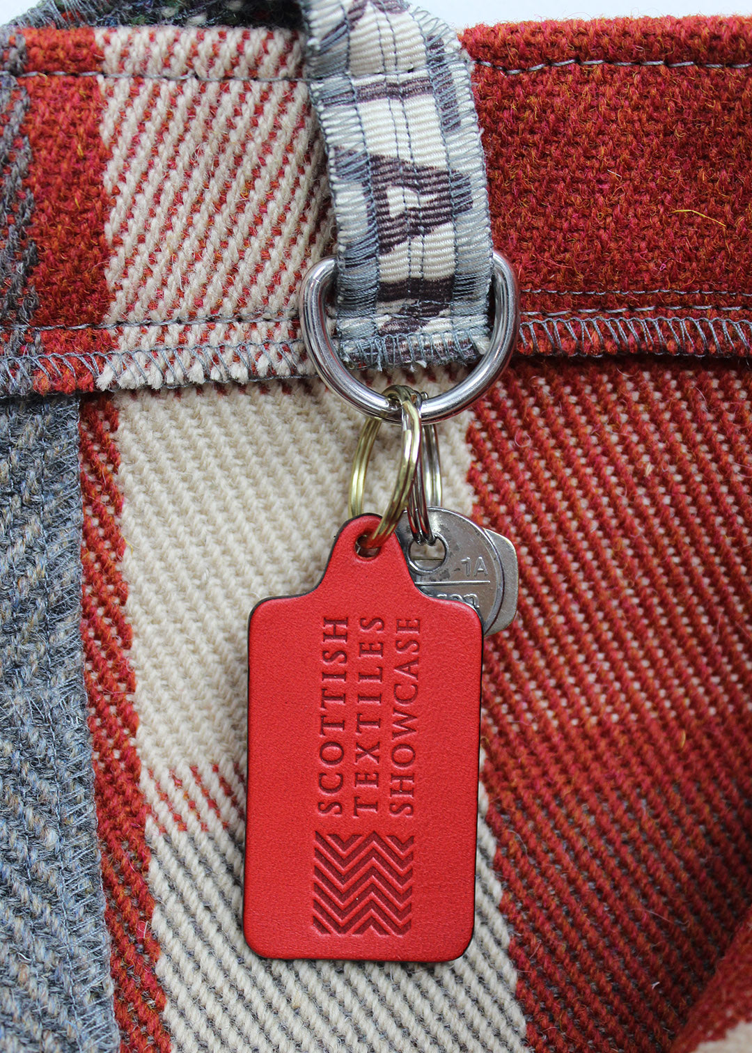 Handcrafted leather key ring in red, embossed with our Scottish Textiles Showcase logo.
