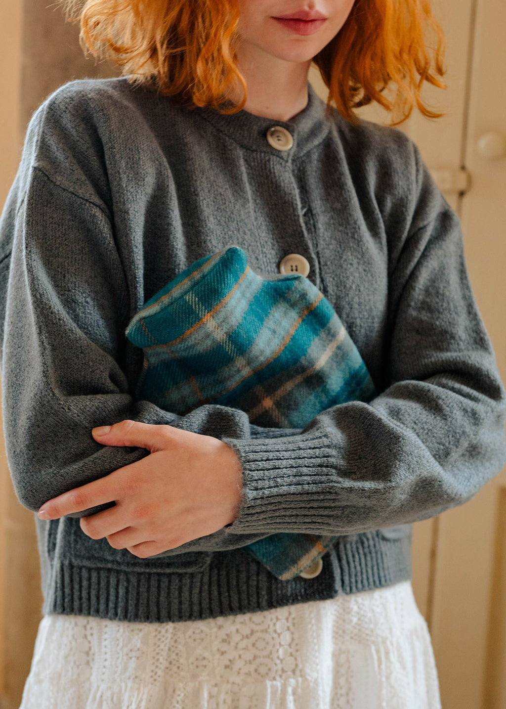 Model holding a lambswool teal tartan hot water bottle.
