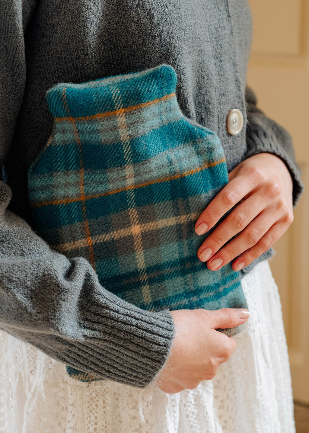 Model holding a lambswool teal tartan hot water bottle.