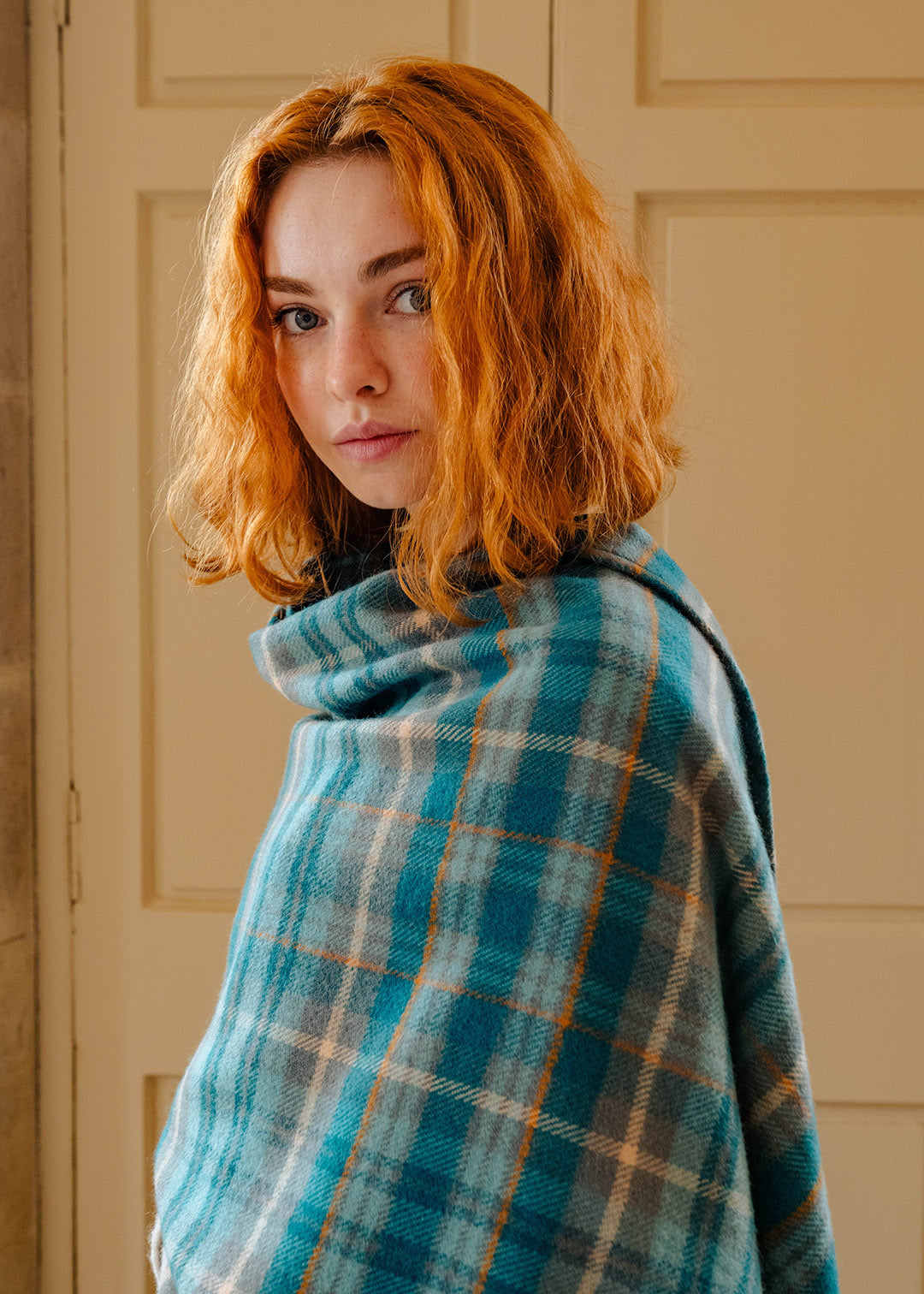 Model wearing a lambswool teal tartan serape.