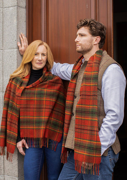 Autumn Woodland Walk tartan scarf on male model and shawl on female model in front of wooden door.