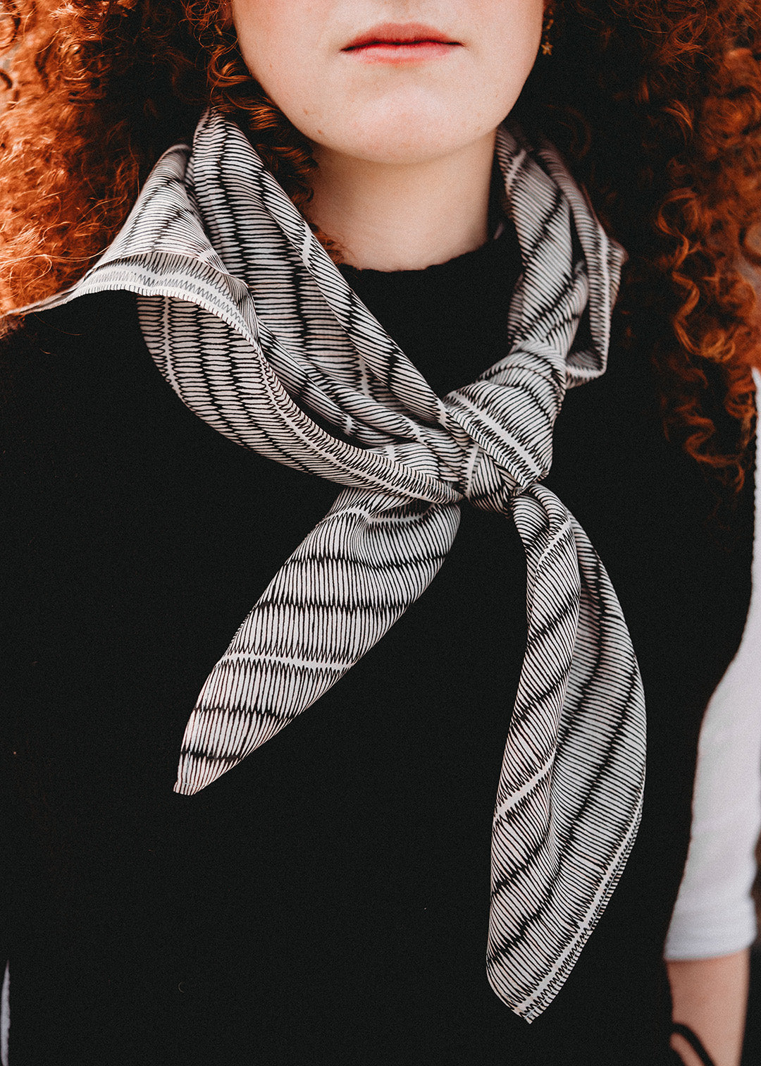 Large silk square scarf with black and white repeat pattern.