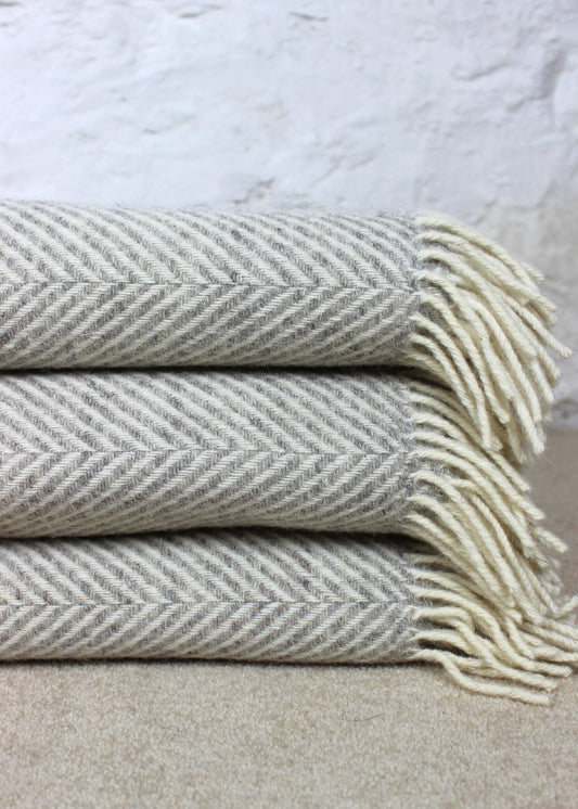 Silver grey blanket with tassels and geometric zig zag pattern. Scottish Textiles Showcase.