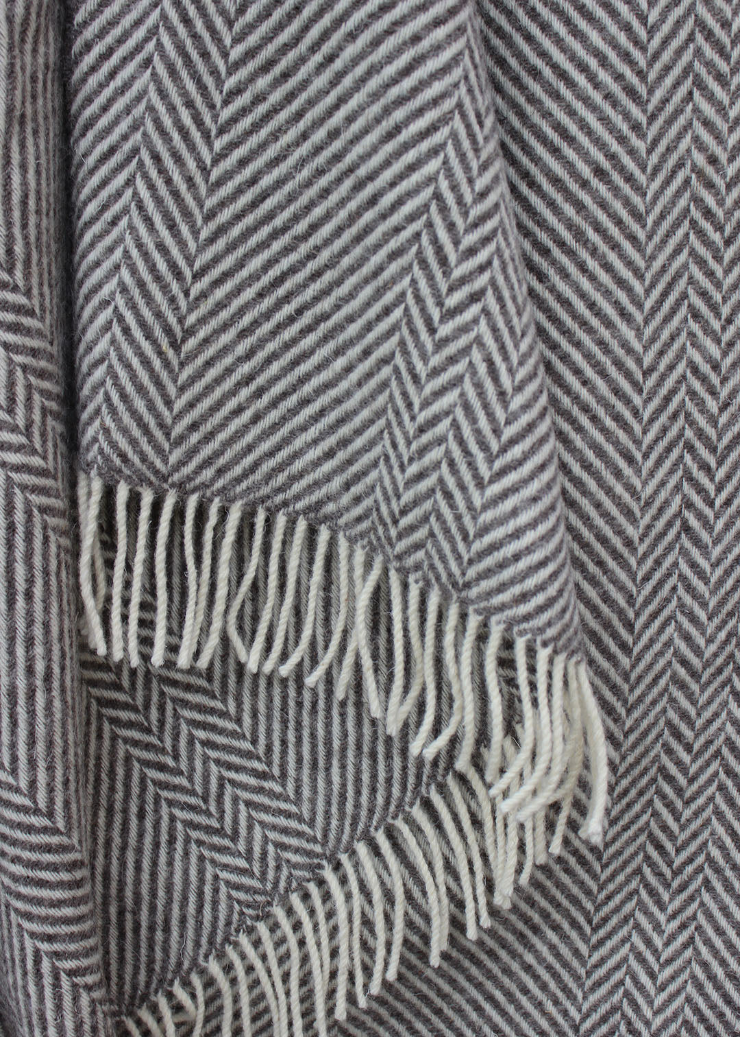 Grey blanket with tassels and geometric zig zag pattern. Scottish Textiles Showcase.