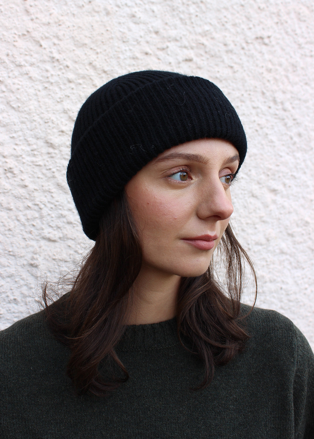 Black ribbed lambswool beanie shown on model. Scottish Textiles Showcase.