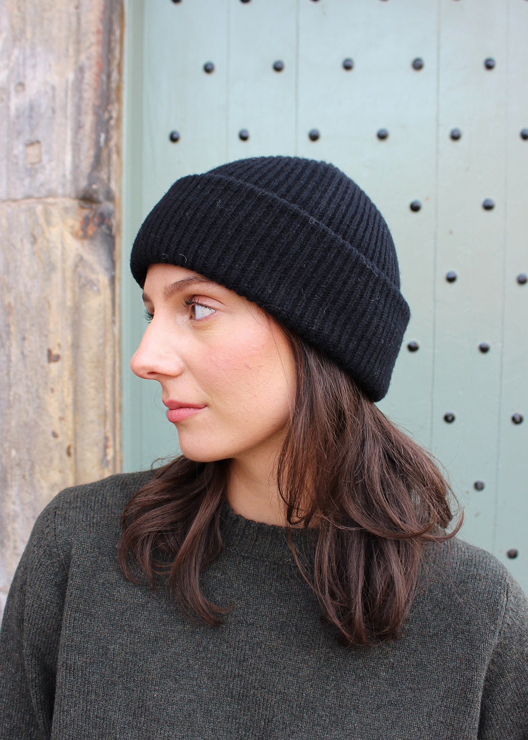 Black ribbed lambswool beanie shown on model. Scottish Textiles Showcase.