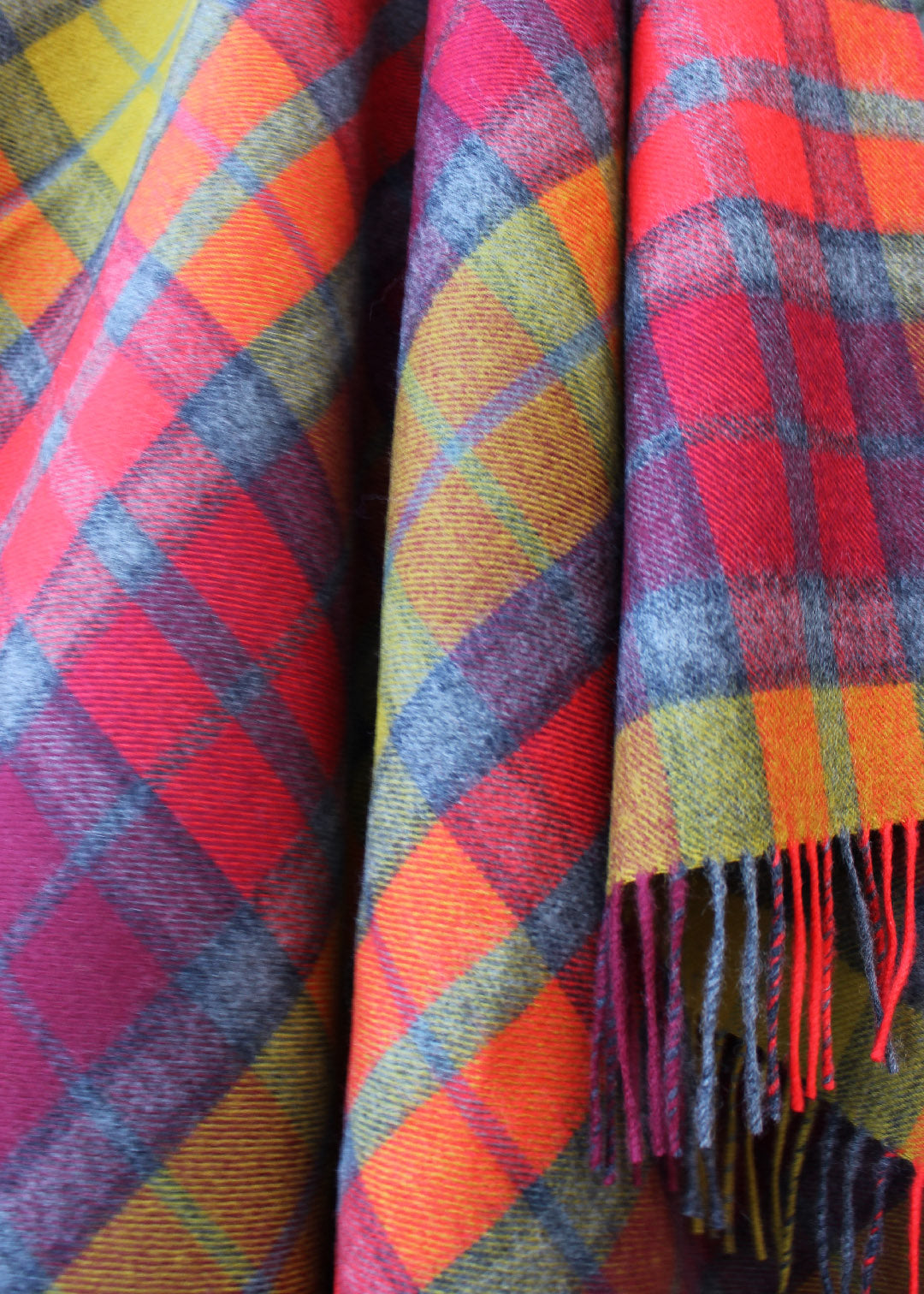 Lambswool tartan blanket woven in the bright reds. yellows and greys of the Buchanan Berry tartan. Made in the Scottish Borders. Scottish Textiles Showcase.