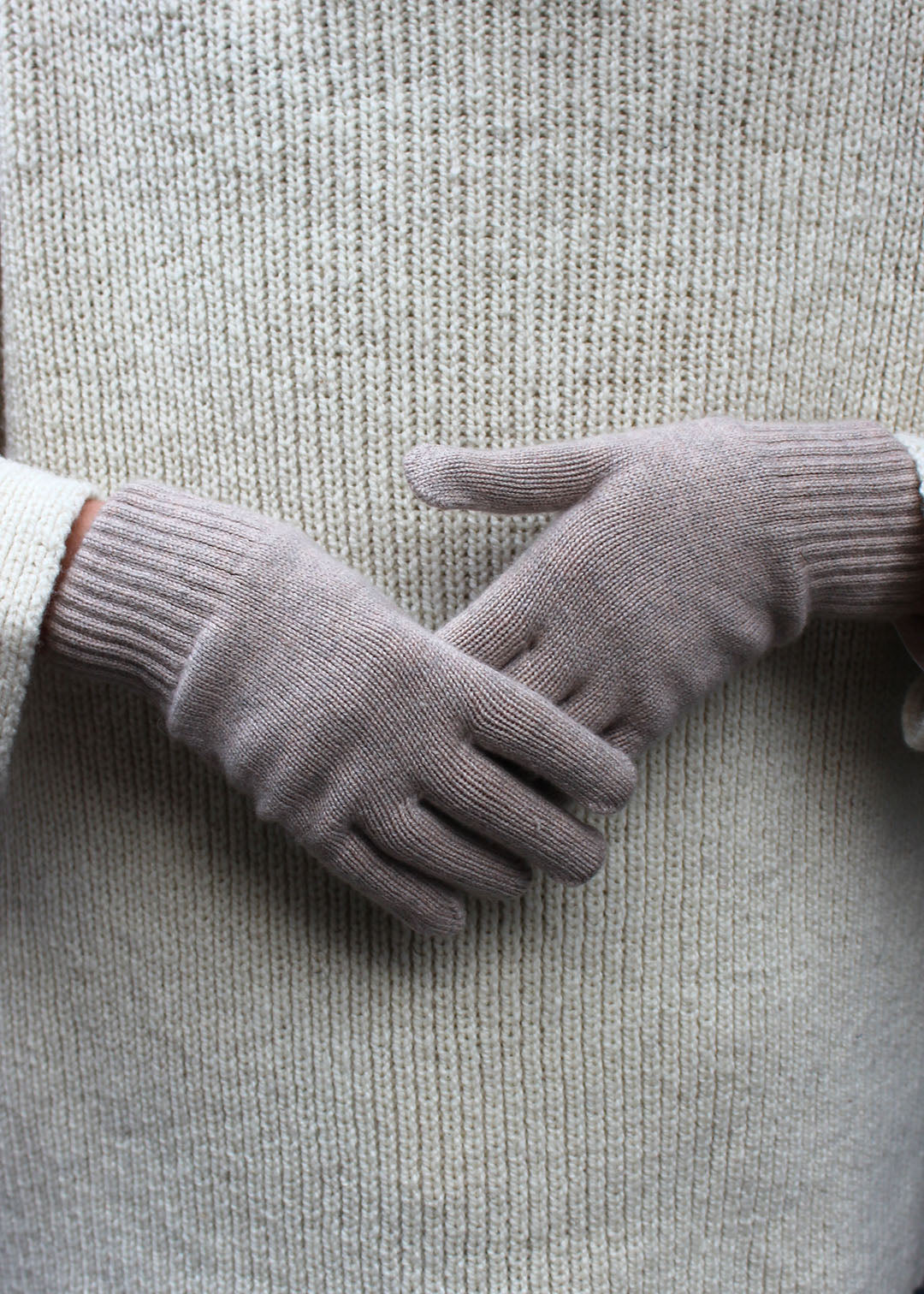 Pair of oatmeal cashmere gloves on model.