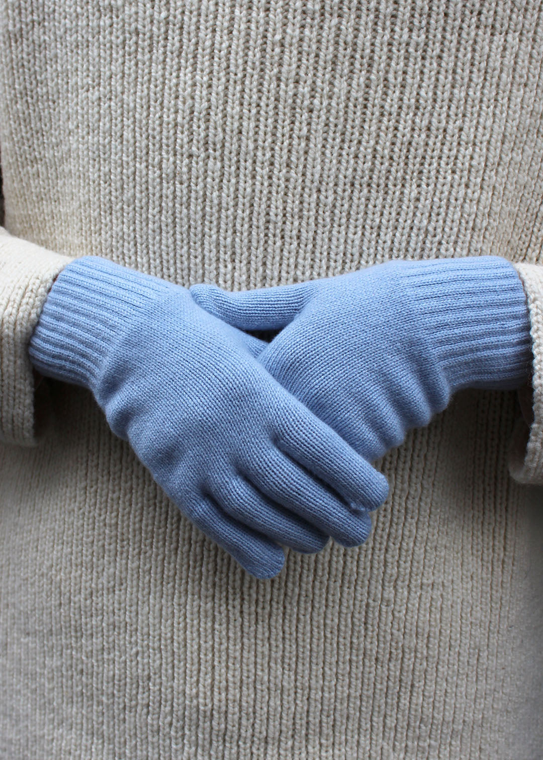 Pair of powder blue cashmere gloves on model.
