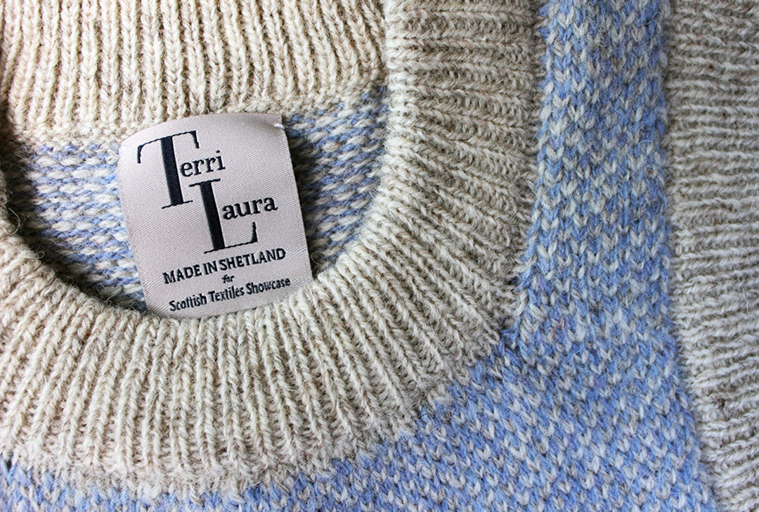 Shetland knitted tank top in pale blue and natural pale grey wool with round neck. Label with Scottish Textile Showcase and Terri Laura branding.
