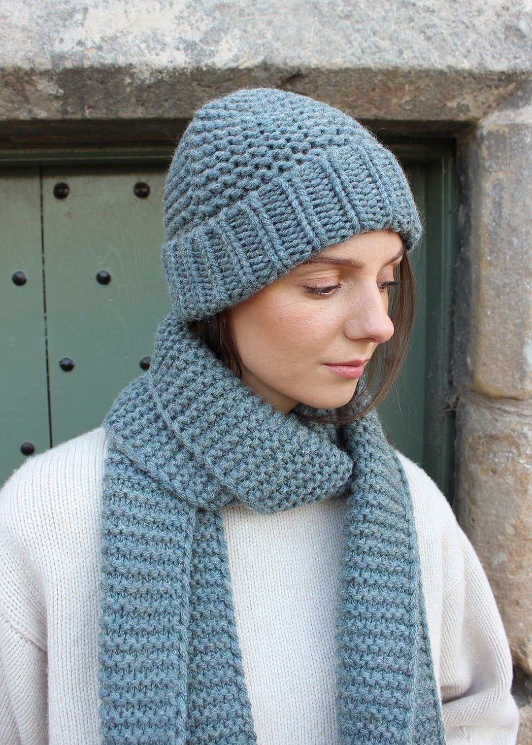 British wool chunky steel blue knitted scarf modelled with matching hat. Scottish Textiles Showcase.