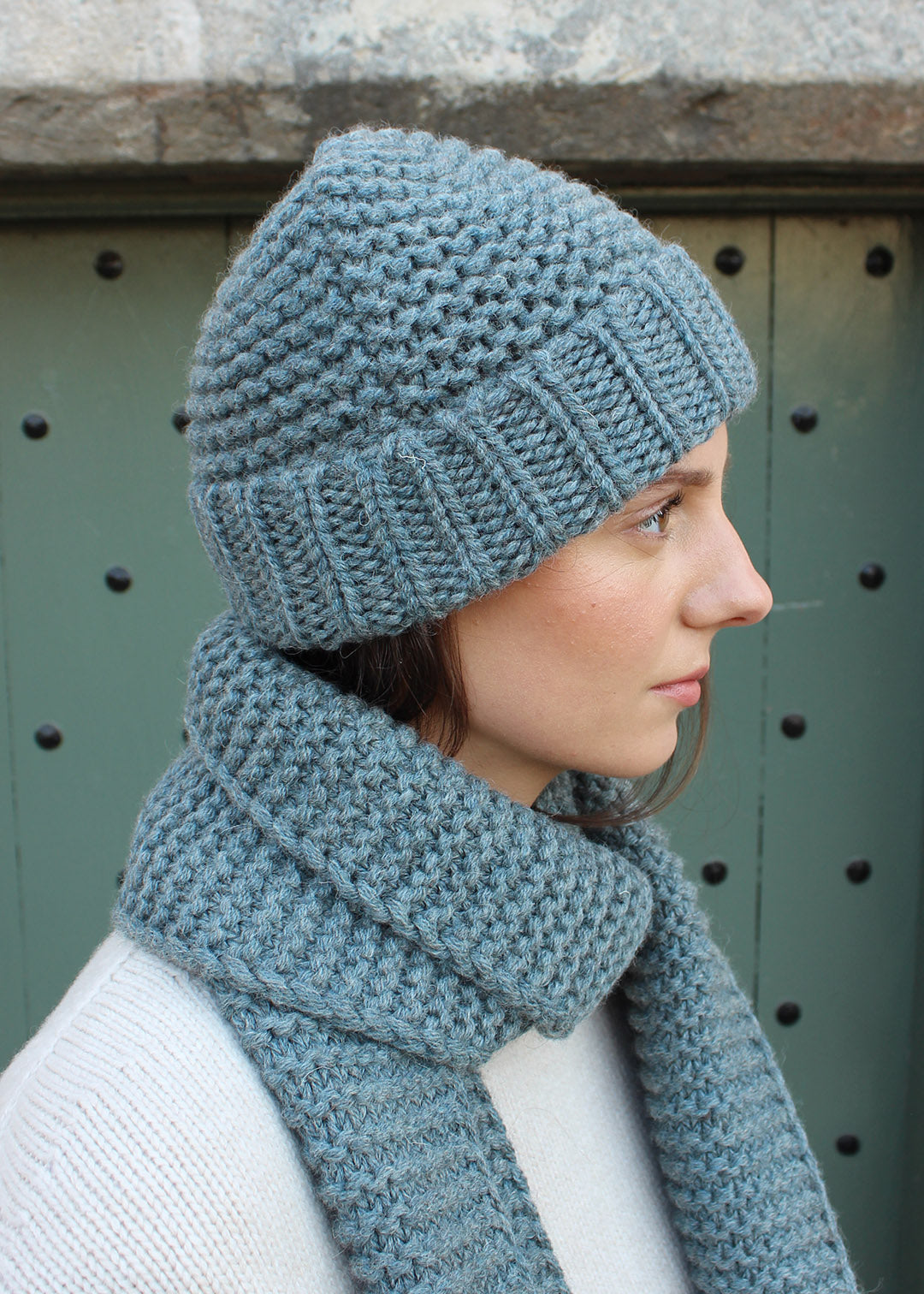 British wool chunky steel blue knitted hat modelled with matching scarf. Scottish Textiles Showcase.