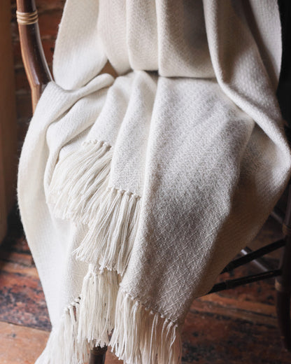 Araminta Campbell kingsize undyed alpaca throw in Woodland Inkcap pattern. Shown in rustic wooden interior.