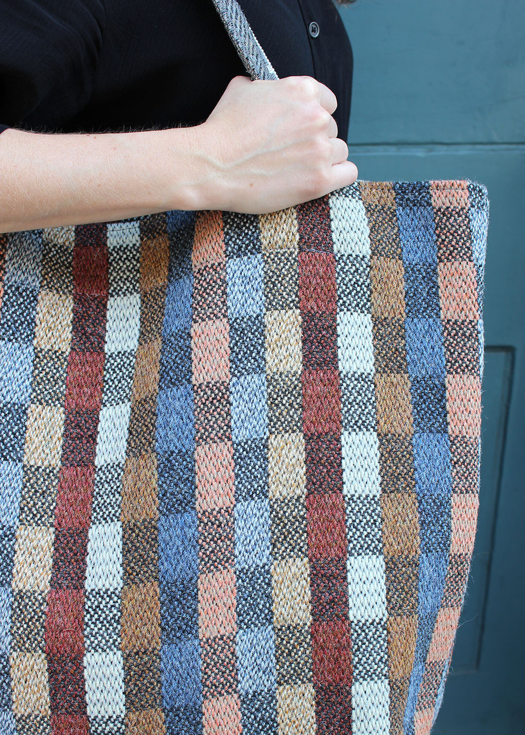 The Benbecula bag is woven in a colourful check with shades of blue, brown, red and black.