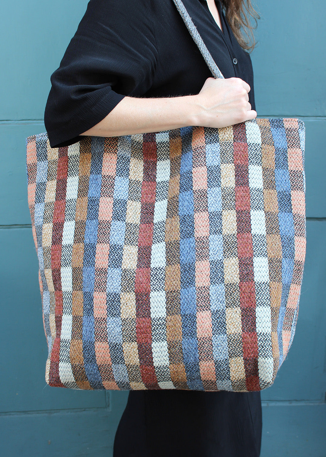 The Benbecula bag is woven in a colourful check with shades of blue, brown, red and black.
