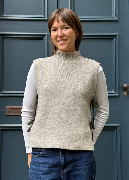 Oat knitted Flora Studio vest with olive green ties shown on model. 