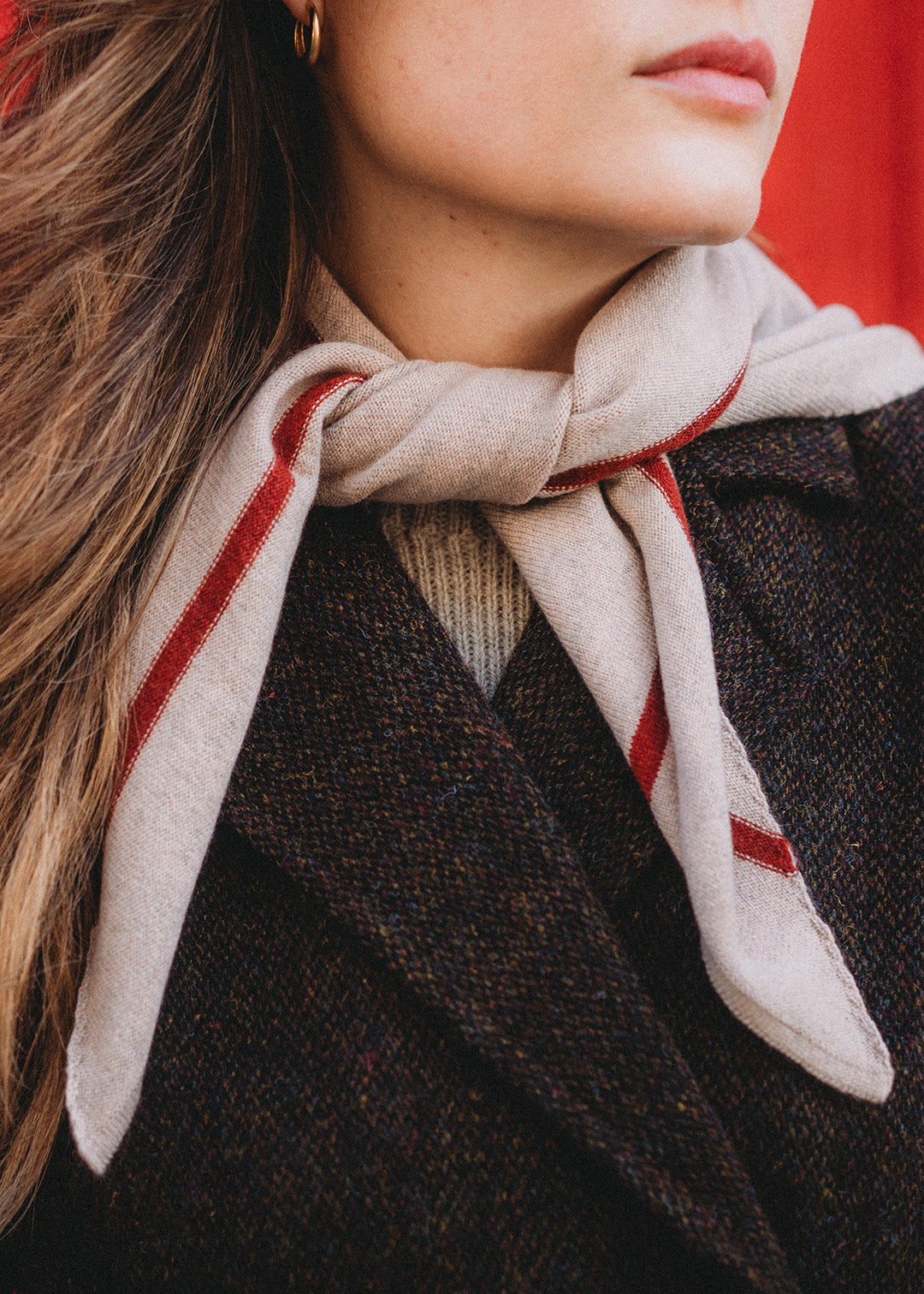 Knitted triangle scarf in fawn with a rust red stripe.