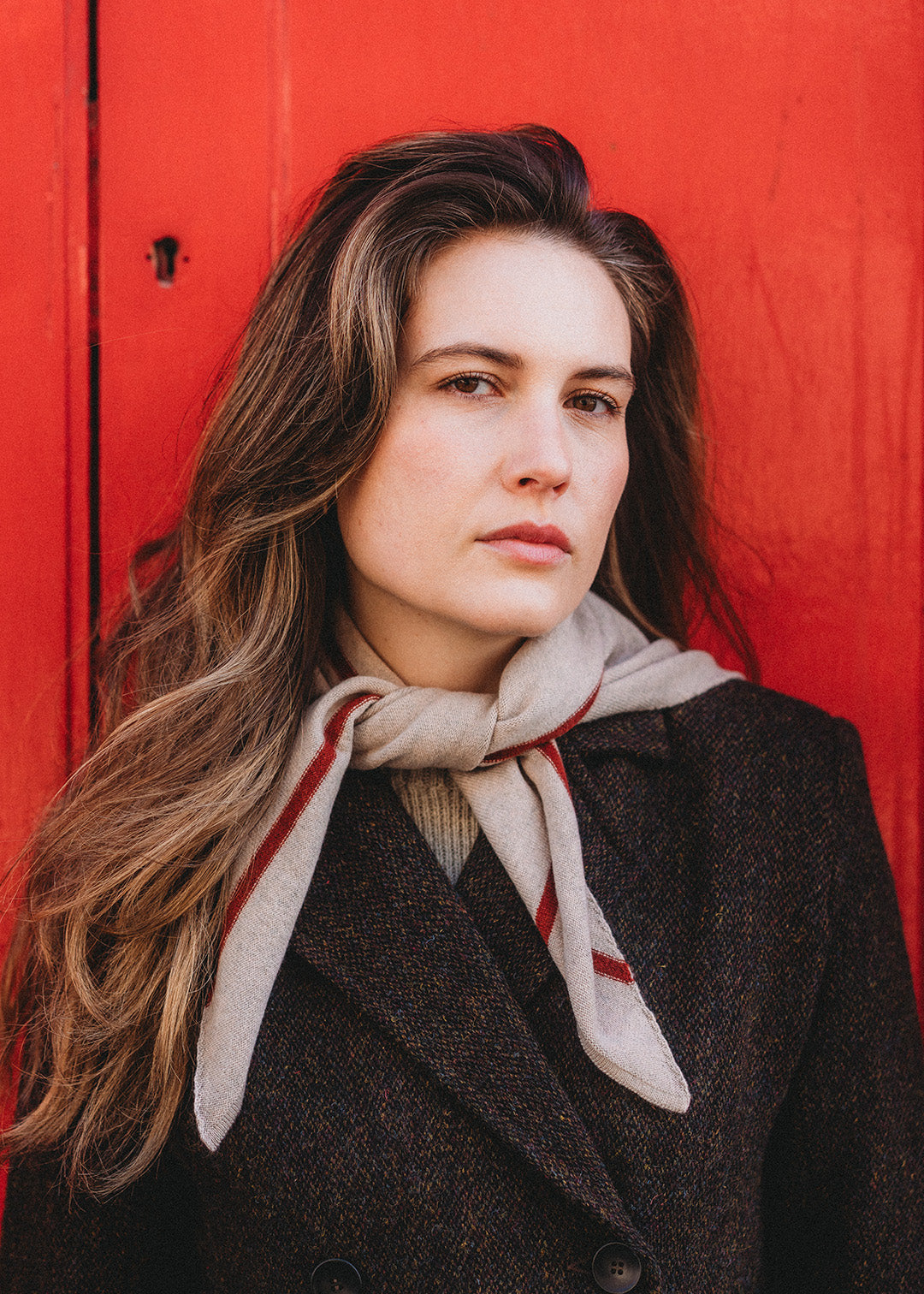 Knitted triangle scarf in fawn with a rust red stripe.