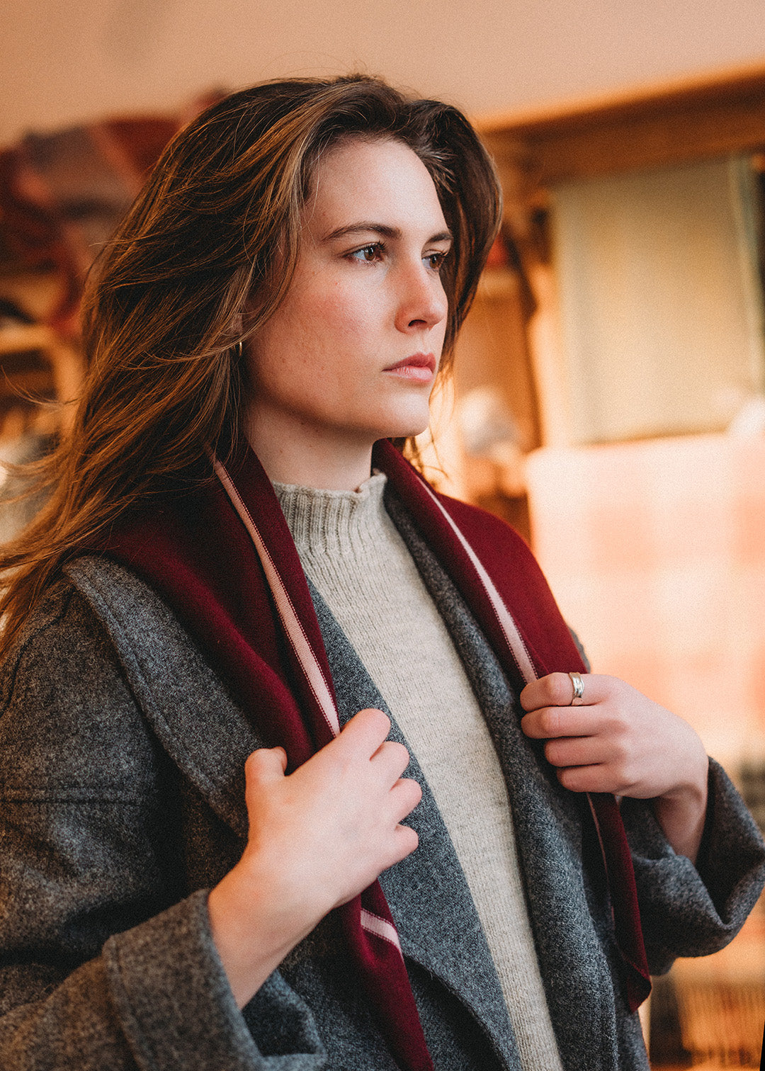 Knitted triangle scarf in deep damson red with a pale pink stripe.