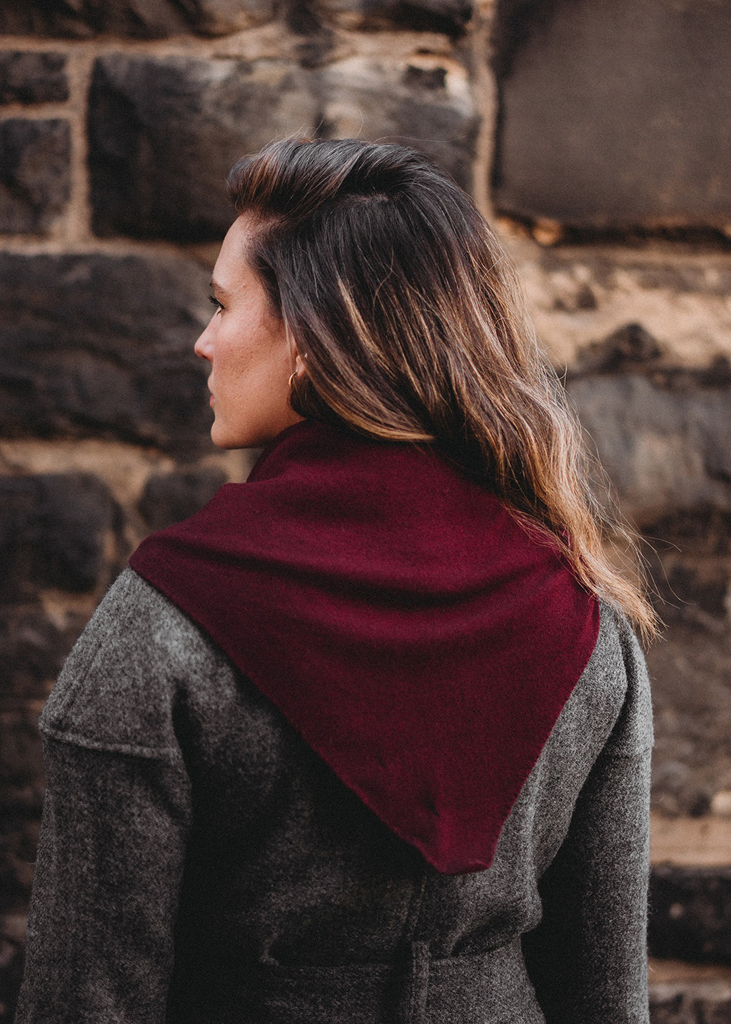 Knitted triangle scarf in deep damson red with a pale pink stripe.