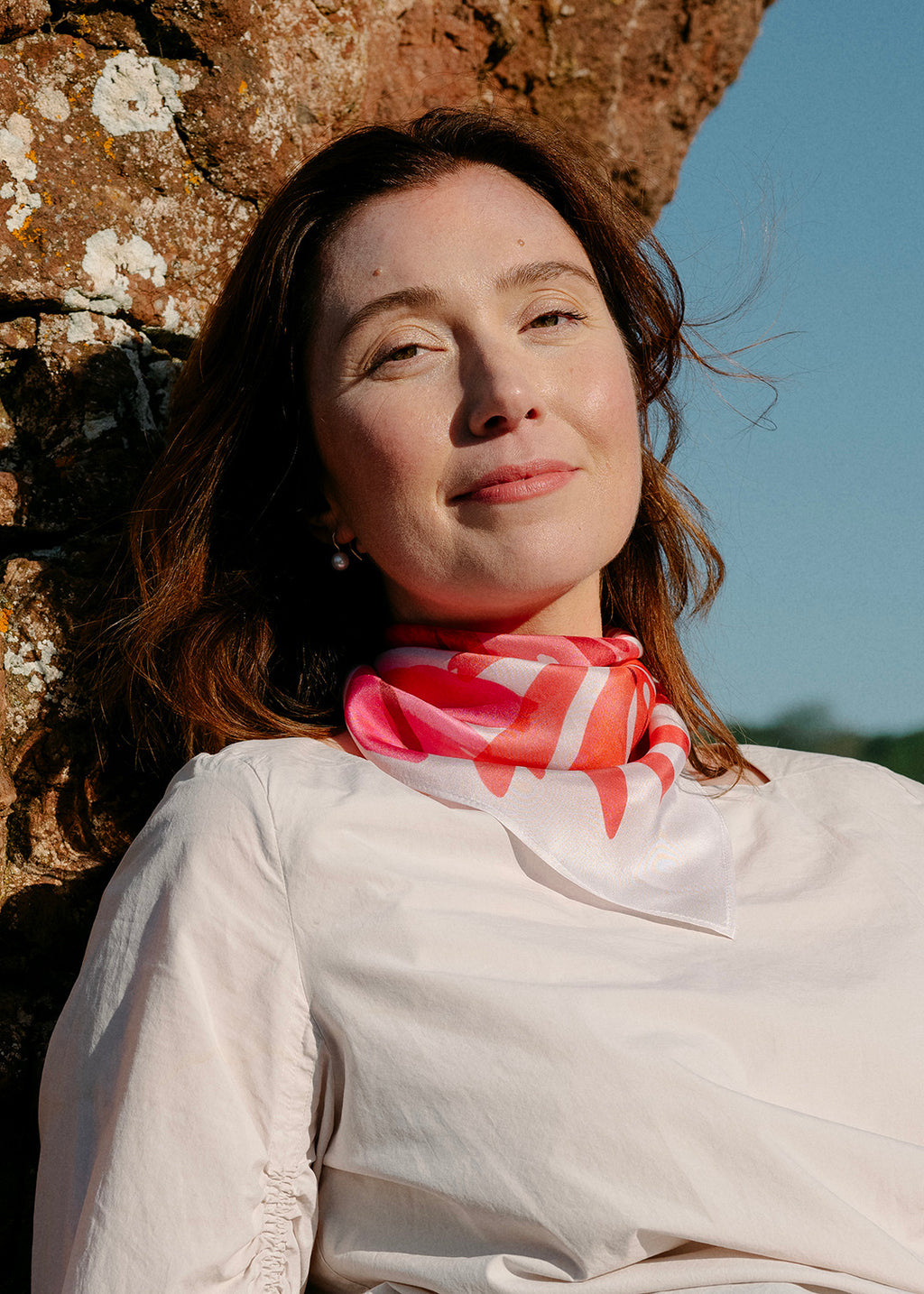 The Dulse silk scarf features a collaged print of dulse seaweed in vibrant pinks on a pearl white background.
