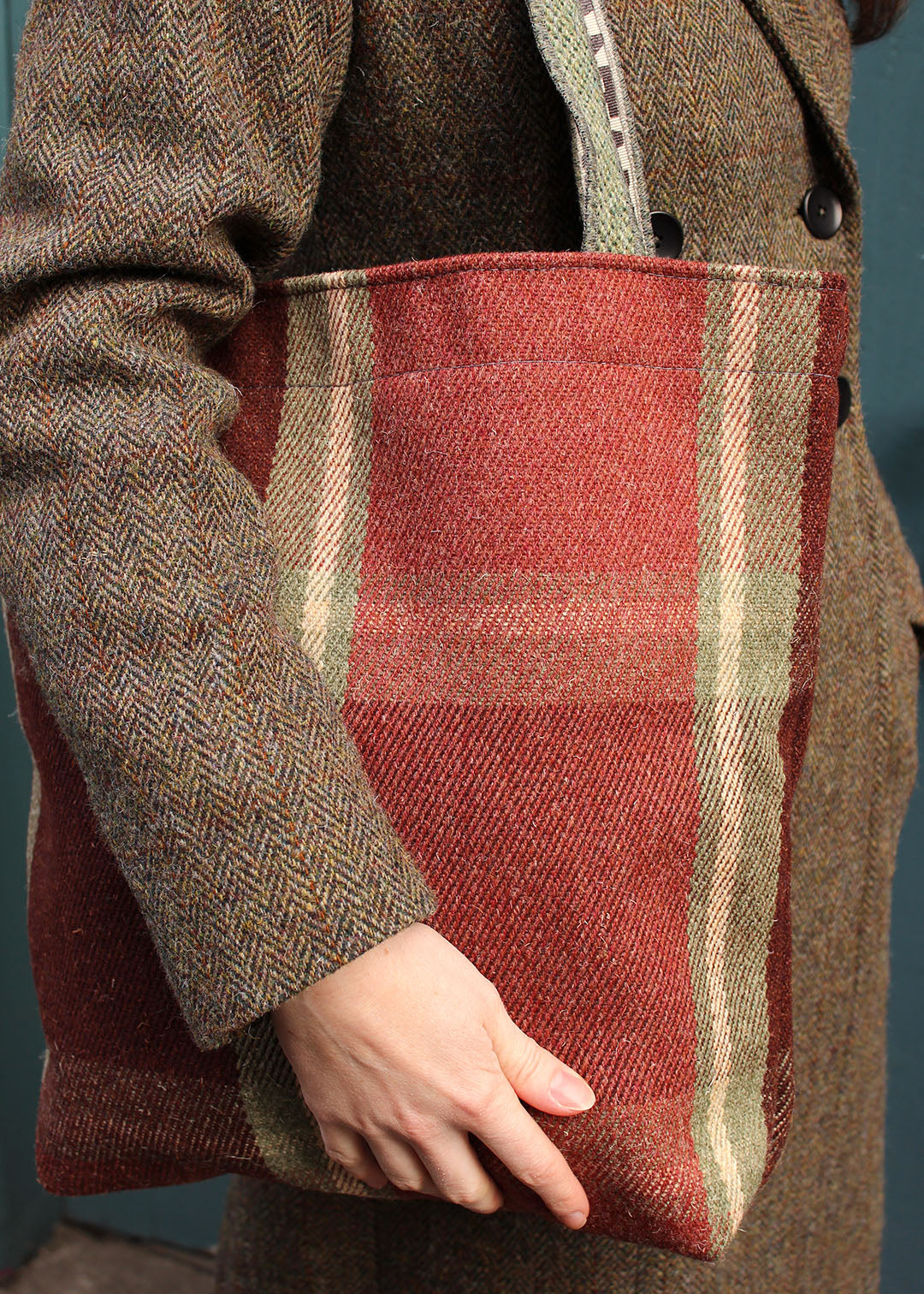 The Dunvegan bag is woven in an oversized check in burgundy, rusty red and sage green.