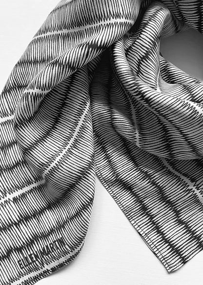 Large silk square scarf with black and white repeat pattern.