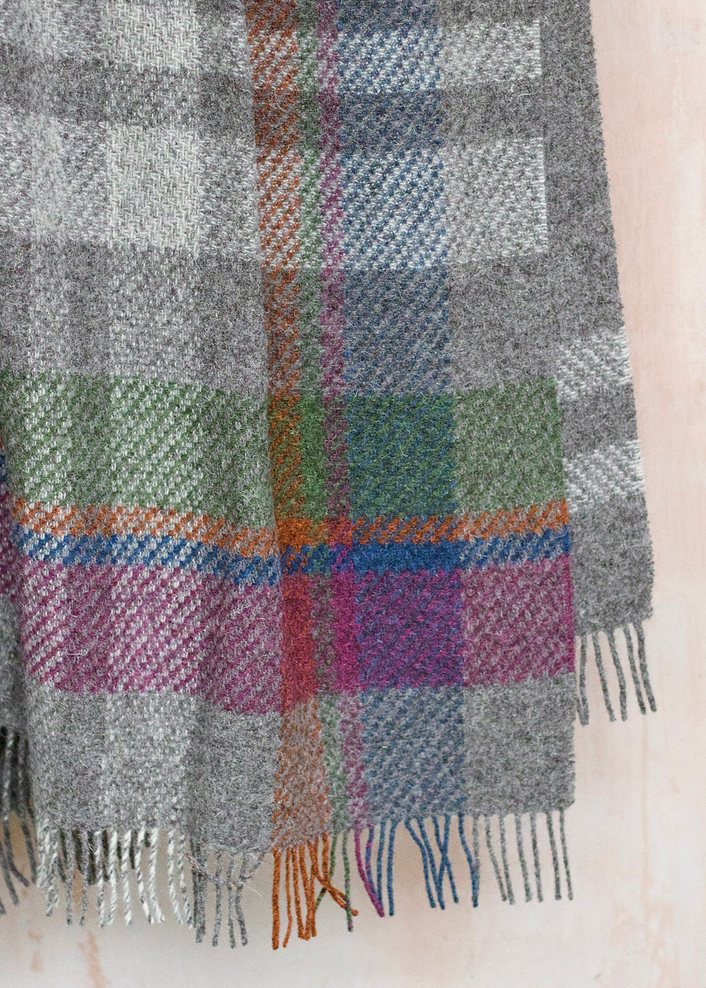 Rustic throw in un-dyed grey and cream Herdwick wool, with a colourful asymmetric check.