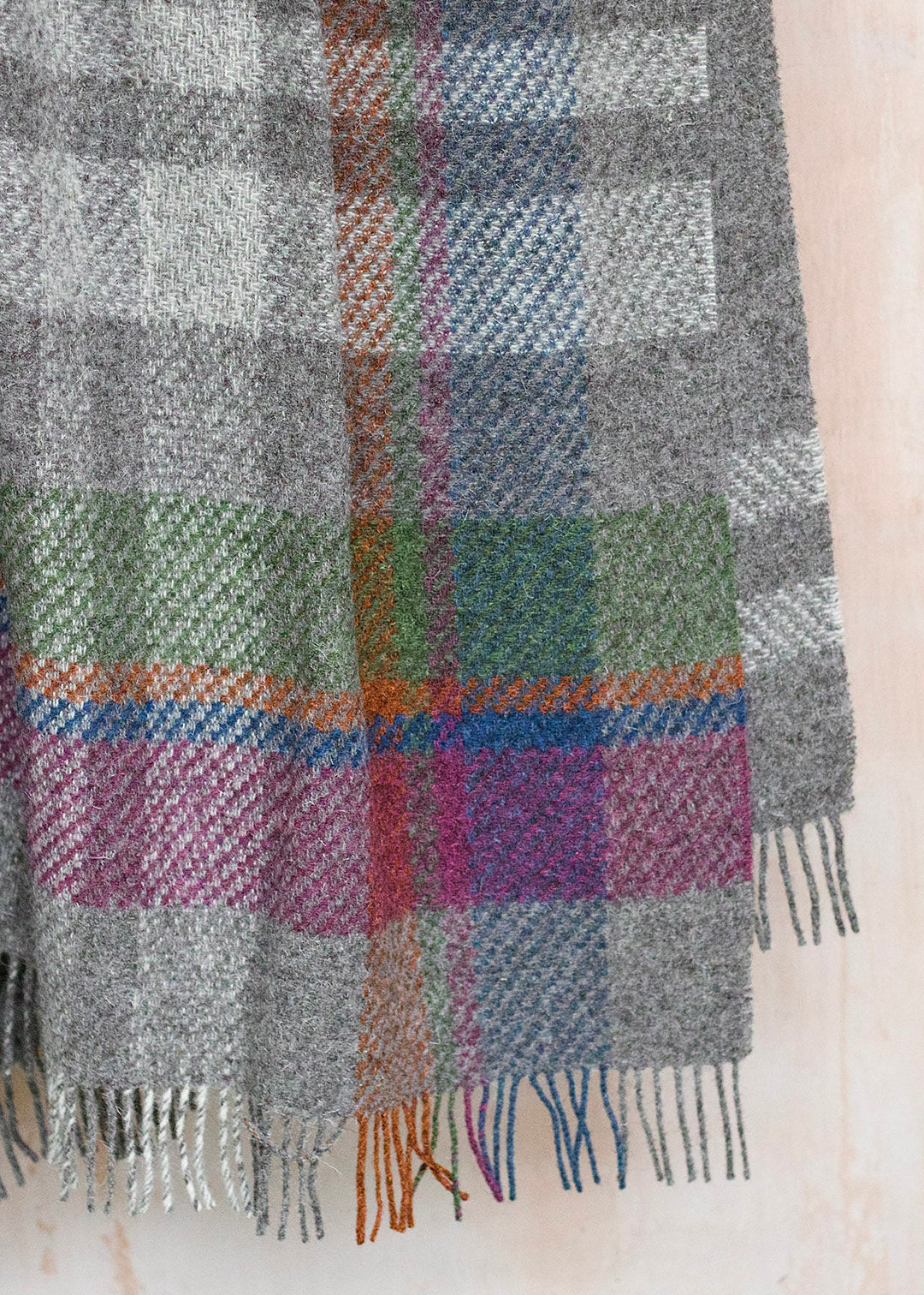 Rustic throw in un-dyed grey and cream Herdwick wool, with a colourful asymmetric check.