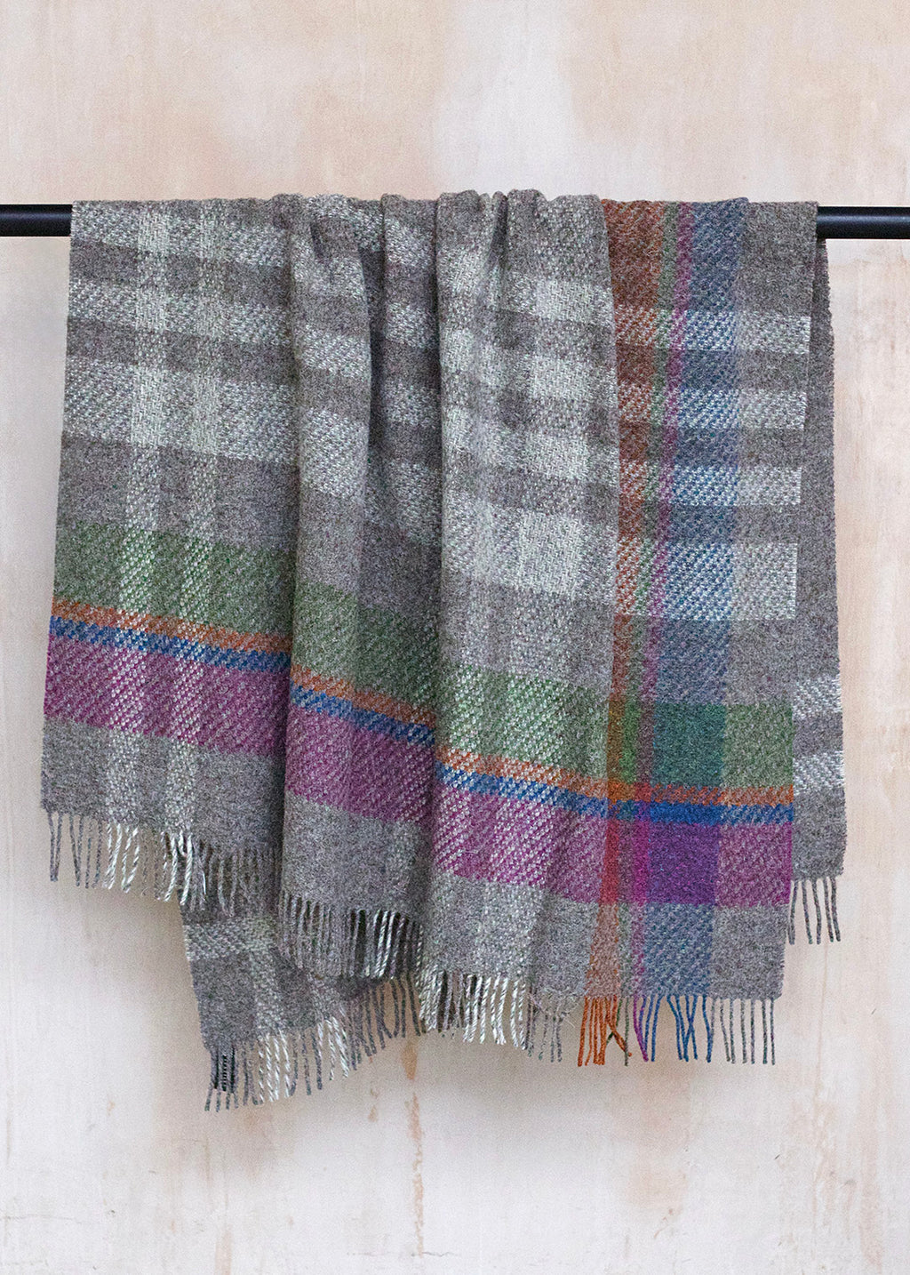 Rustic throw in un-dyed grey and cream Herdwick wool, with a colourful asymmetric check.