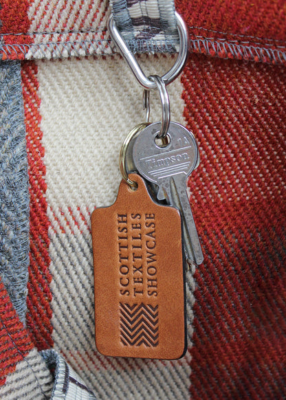 Handcrafted leather key ring in antique tan, embossed with our Scottish Textiles Showcase logo.