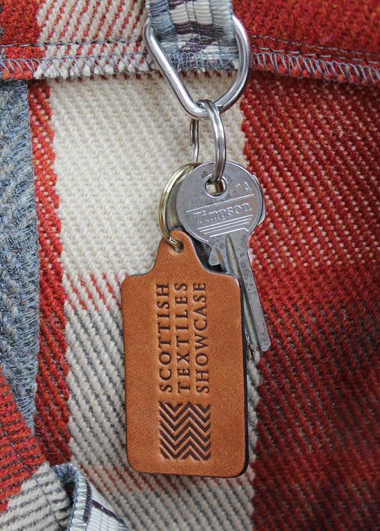 Handcrafted leather key ring in antique tan, embossed with our Scottish Textiles Showcase logo.