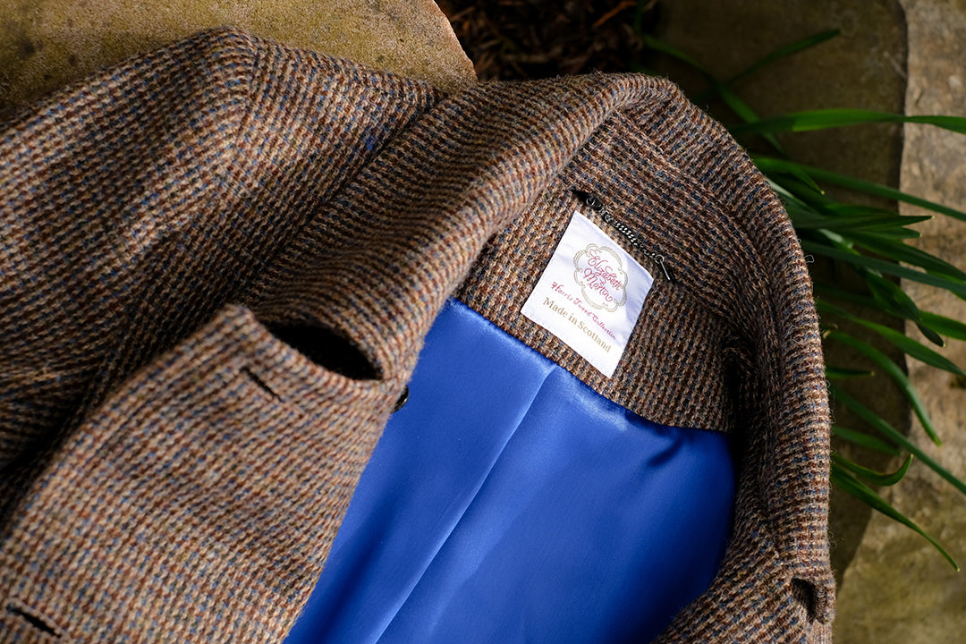 Maxi length Harris Tweed coat featuring offset buttons and a contrasting blue satin lining.