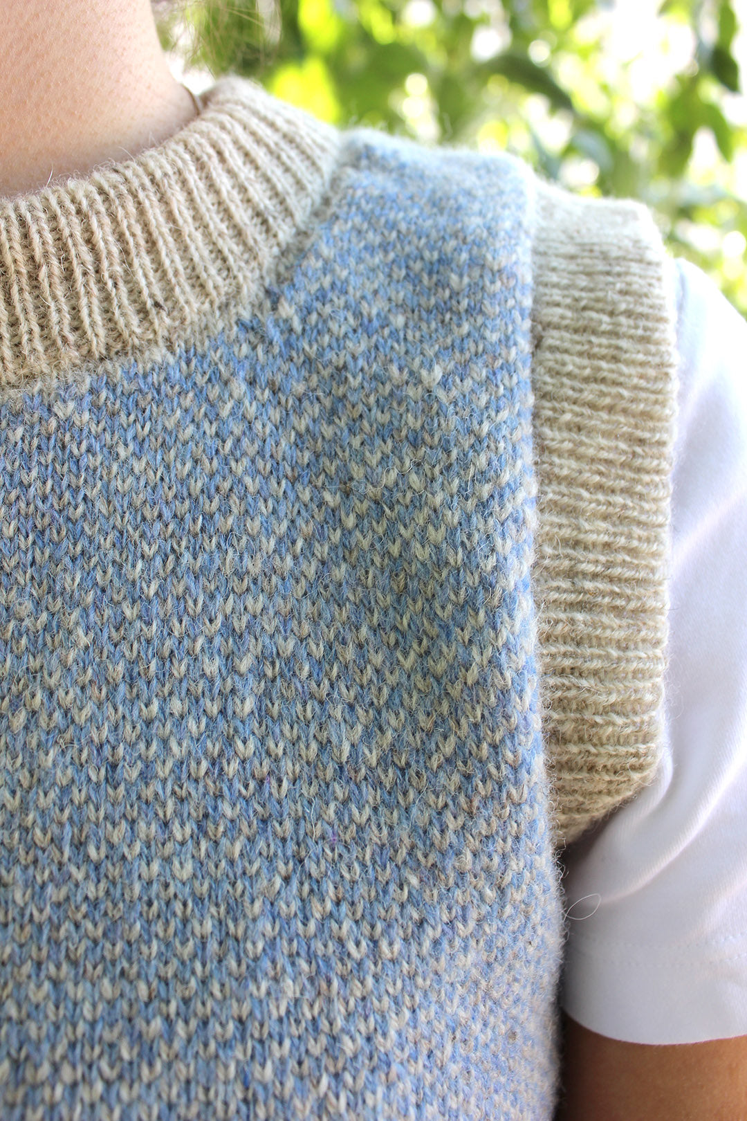 Shetland knitted tank top in pale blue and natural pale grey wool with round neck. Shown close up.