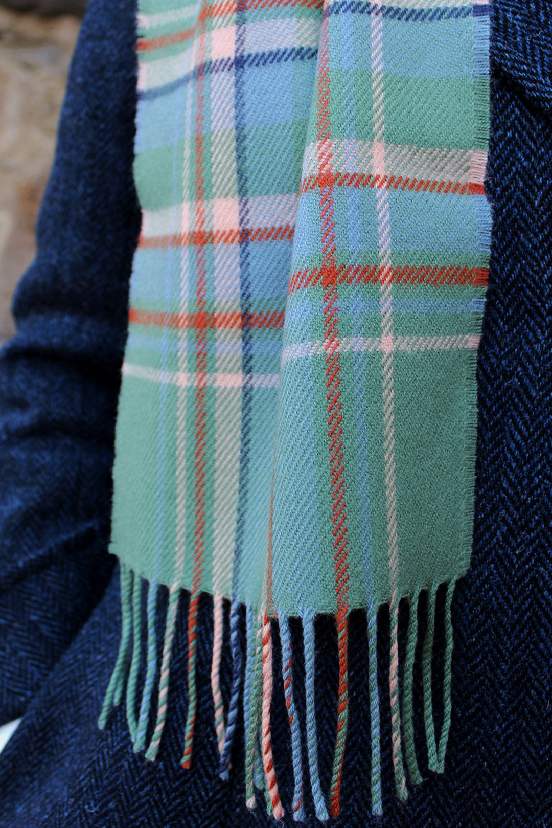Araminta Campebell Highlands at Dawn woven lambswool scarf with tassels. Woven with a hazy shades of green and blue with a touch of burnt orange and peach white . Scottish Textiles Showcase.