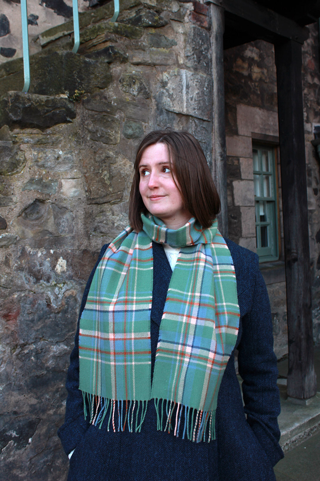 Araminta Campebell Highlands at Dawn woven lambswool scarf with tassels. Woven with a hazy shades of green and blue with a touch of burnt orange and peach white . Scottish Textiles Showcase.