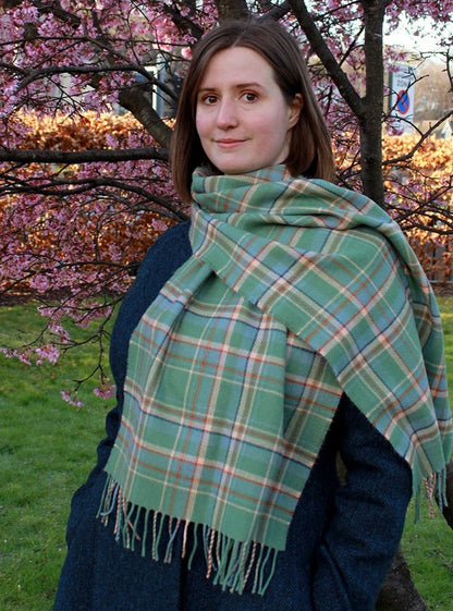 Araminta Campebell Highlands at Dawn woven lambswool shawl with tassels. Woven with a hazy shades of green and blue with a touch of burnt orange and peach white . Scottish Textiles Showcase.
