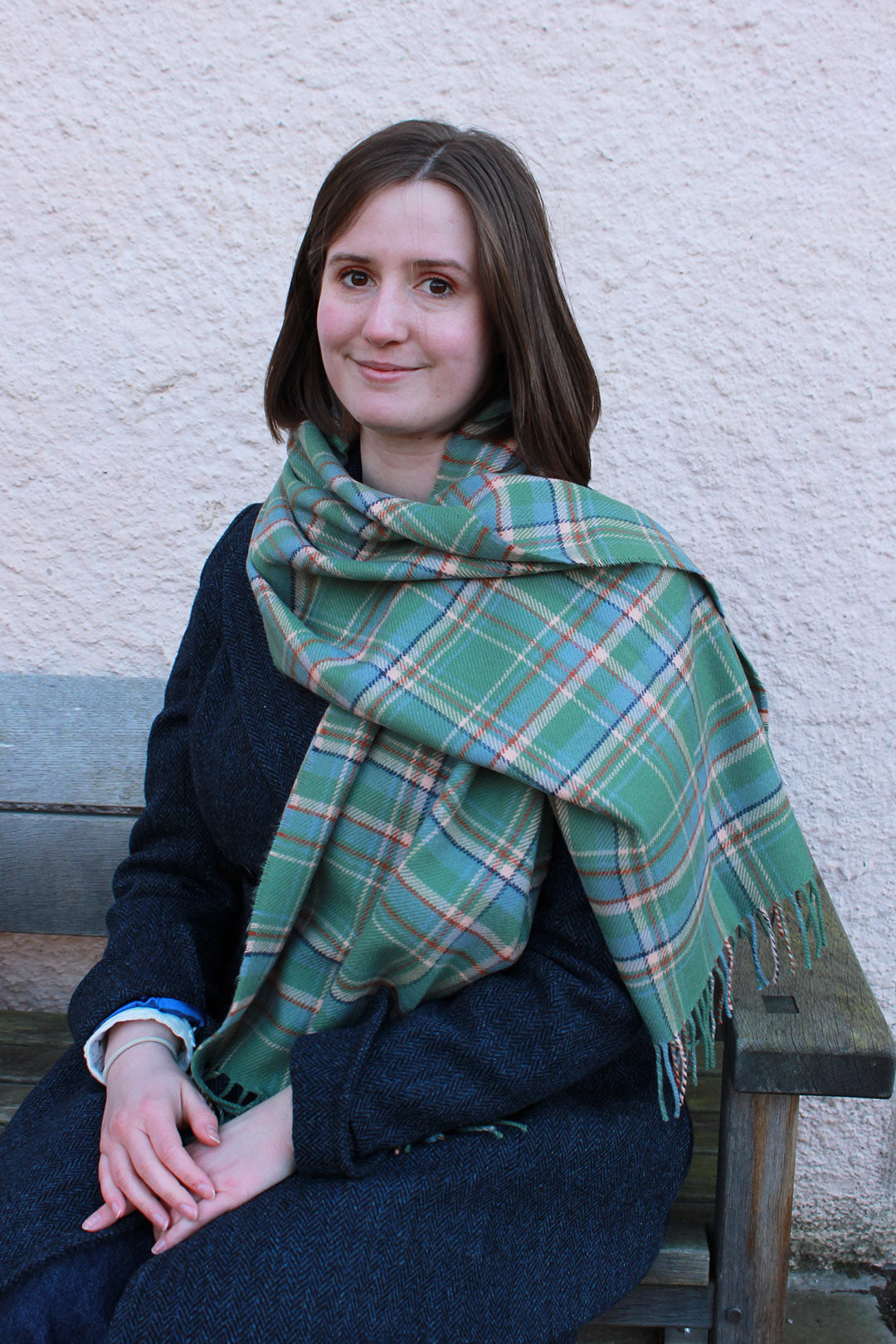 Araminta Campebell Highlands at Dawn woven lambswool shawl with tassels. Woven with a hazy shades of green and blue with a touch of burnt orange and peach white . Scottish Textiles Showcase