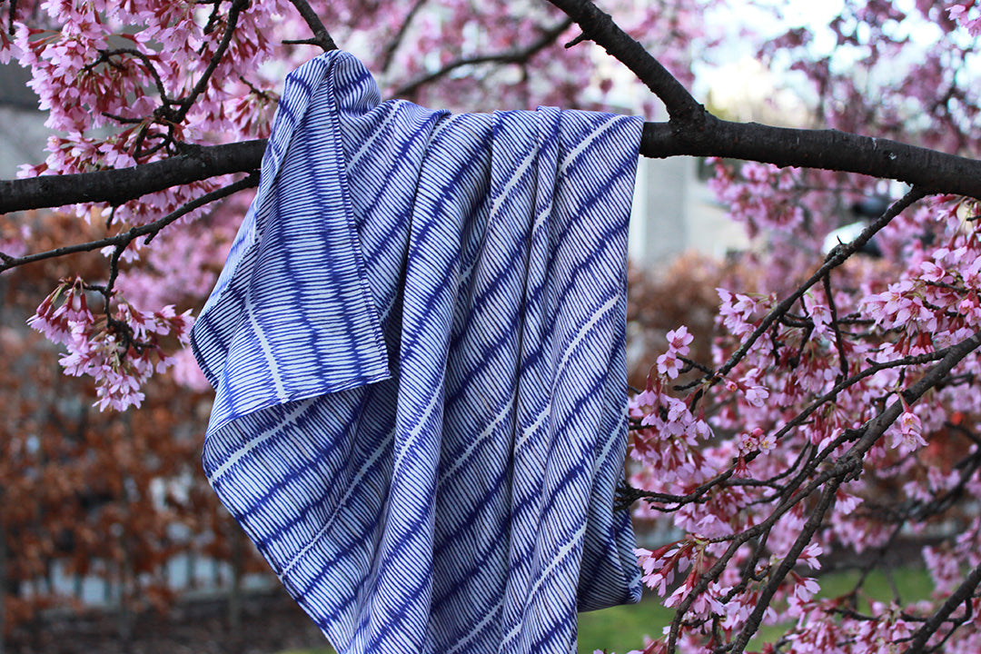 Blue and ivory large silk scarf with intricate hand-drawn print, shown draped on a plain background.