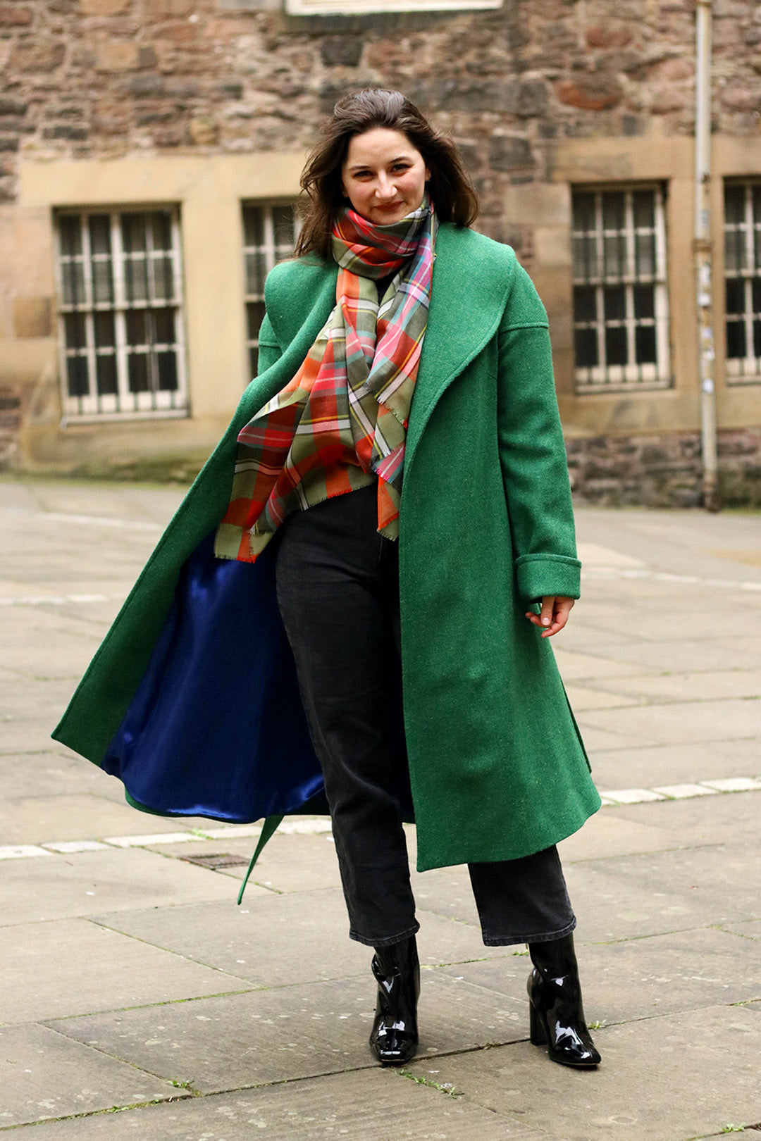 The classic Harris Tweed coat is made in a vibrant emerald green tweed with a royal blue satin lining, shown on model.