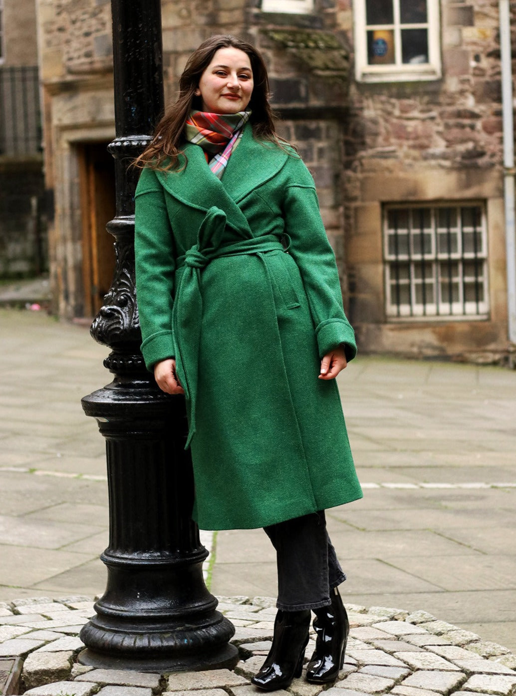The classic Harris Tweed coat is made in a vibrant emerald green tweed with a royal blue satin lining, shown on model.